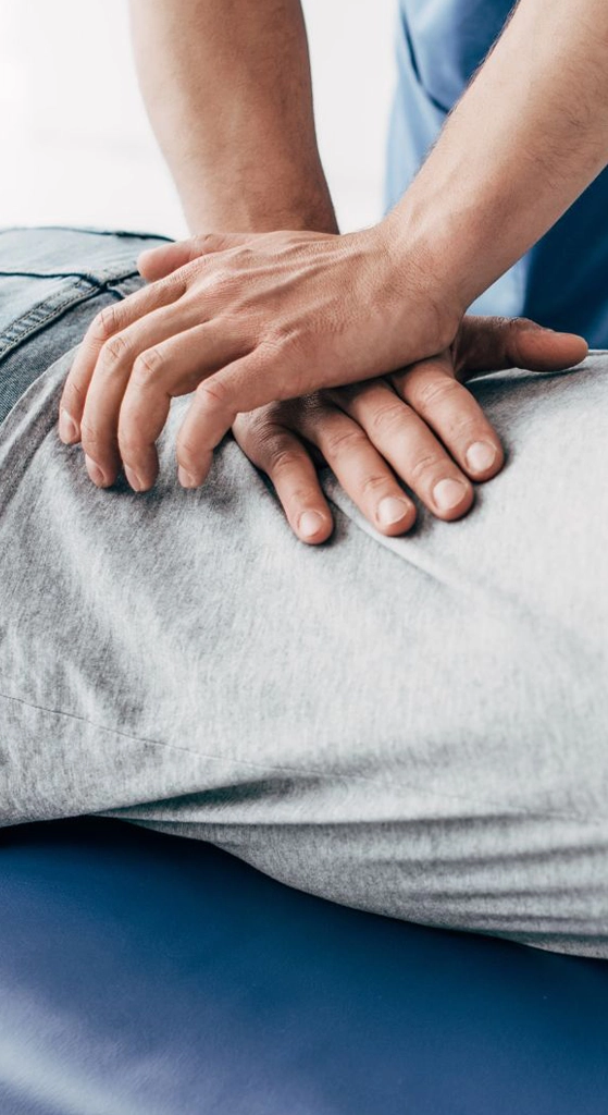 Provider performing hands-on treatment on a patient’s lower back while the patient lies face down on a treatment table for back pain relief.